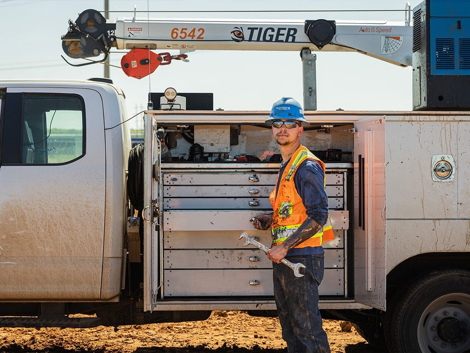 a heavy equipment manager who has been working on renewable energy construction equipment stands beside his work truck on a renewable energy project