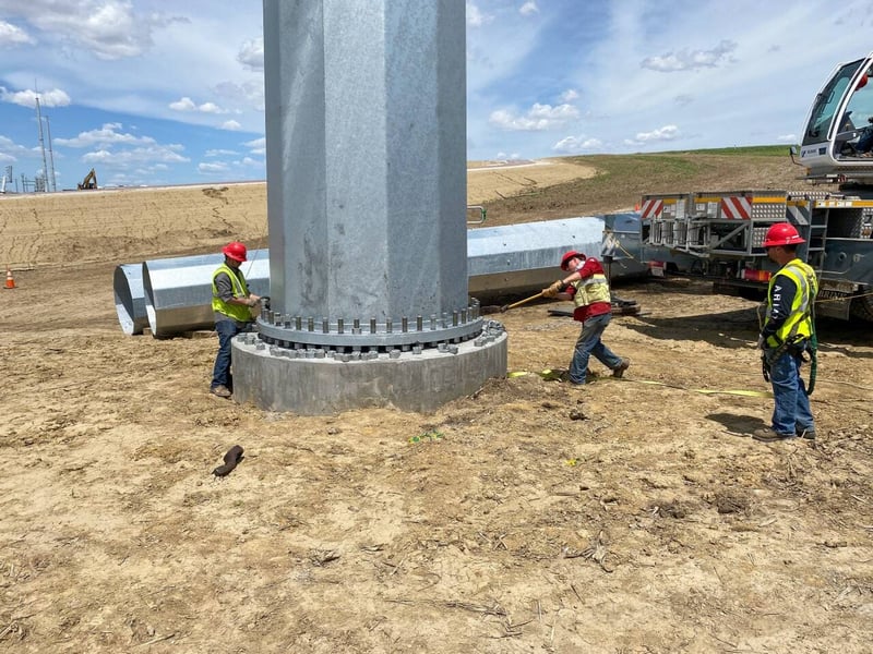 employees on a wind energy project working on securing a tower base of a wind turbine