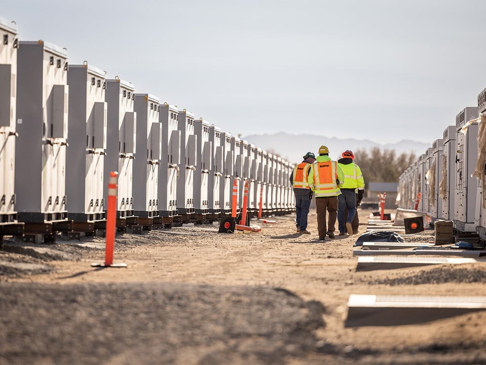 A group of construction workers walking between rows of storage containers